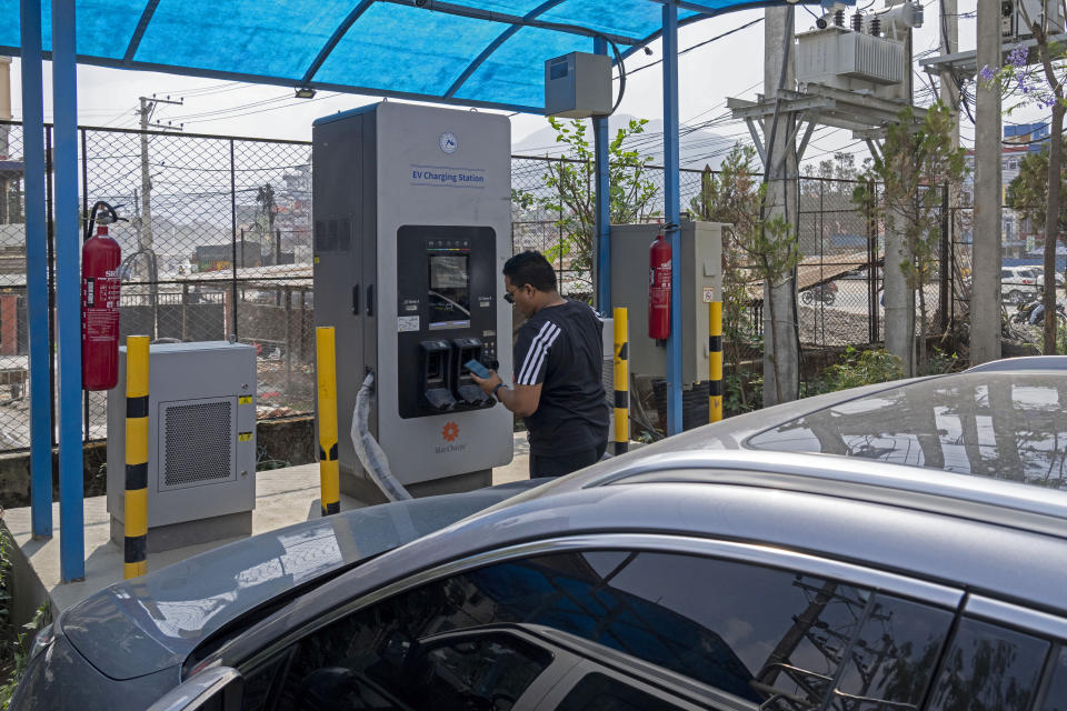 A man charges his electric vehicle at a charging station in Kathmandu, Nepal, Thursday, Tuesday, May 14, 2024. Nearly all of the electricity produced in Nepal is clean energy, most of it generated by river-fed hydro-electricity. Thanks to that abundant source of power, the country is quickly expanding charging networks and imports of EVs have doubled in each of the past two years, according to customs data. (AP Photo/Niranjan Shrestha)