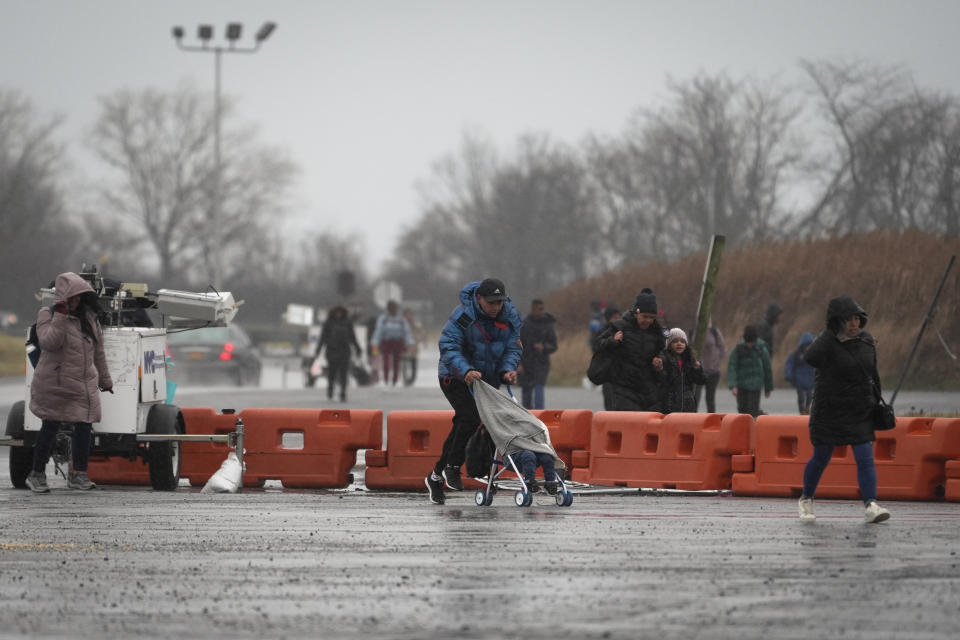 Families rush back to a migrant shelter housed at Floyd Bennett Field before an announced weather-related evacuation, Tuesday, Jan. 9, 2024, in the Brooklyn borough of New York. (AP Photo/John Minchillo)