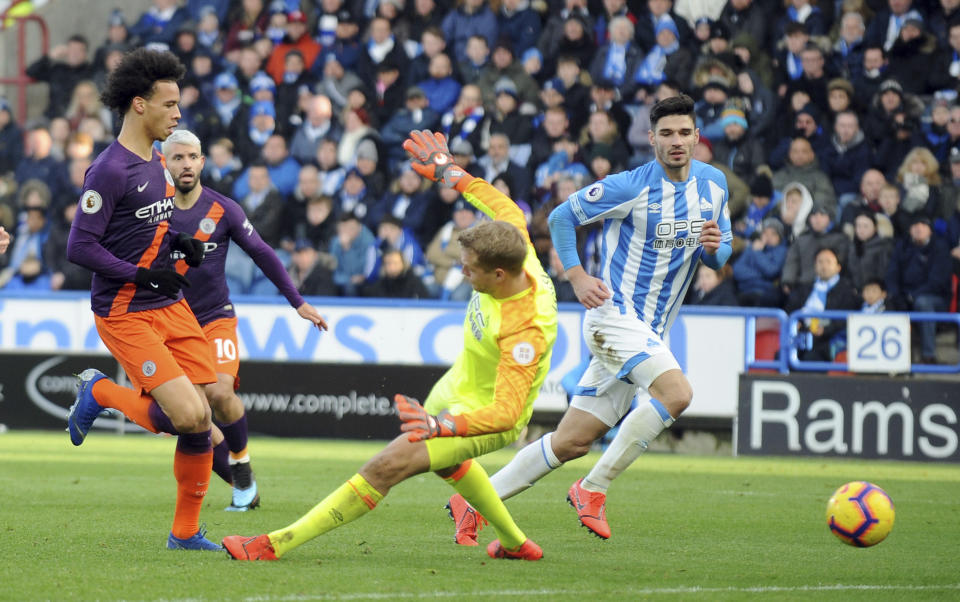 El extremo del Manchester City, Leroy Sané, toca el balón ante la salida del portero del Huddersfield Town, Jonas Lossl, para anotar el tercer gol de su equipo durante un partido de la Liga Premier inglesa en el estadio John Smith en Huddersfield, Inglaterra, el domingo 20 de enero de 2019. (AP Foto/Rui Vieira)