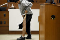 Former Marjory Stoneman Douglas High School student Anthony Borges, who was injured in the 2018 shootings, unsnaps his pant leg to show the scars from his injuries while testifying during the trial of former Marjory Stoneman Douglas High School School Resource Officer Scot Peterson, Thursday, June 8, 2023, at the Broward County Courthouse in Fort Lauderdale, Fla. Peterson is charged with child neglect and other charges for failing to stop the Parkland school massacre five years ago. (Amy Beth Bennett/South Florida Sun-Sentinel via AP, Pool)