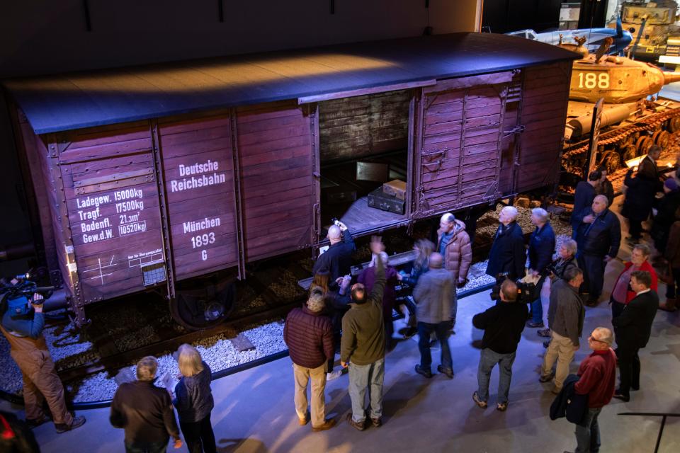 Visitors examine a German-built rail car that's part of an exhibit on the Holocaust during an induction ceremony at the American Heritage Museum in Hudson, Jan. 19, 2024.