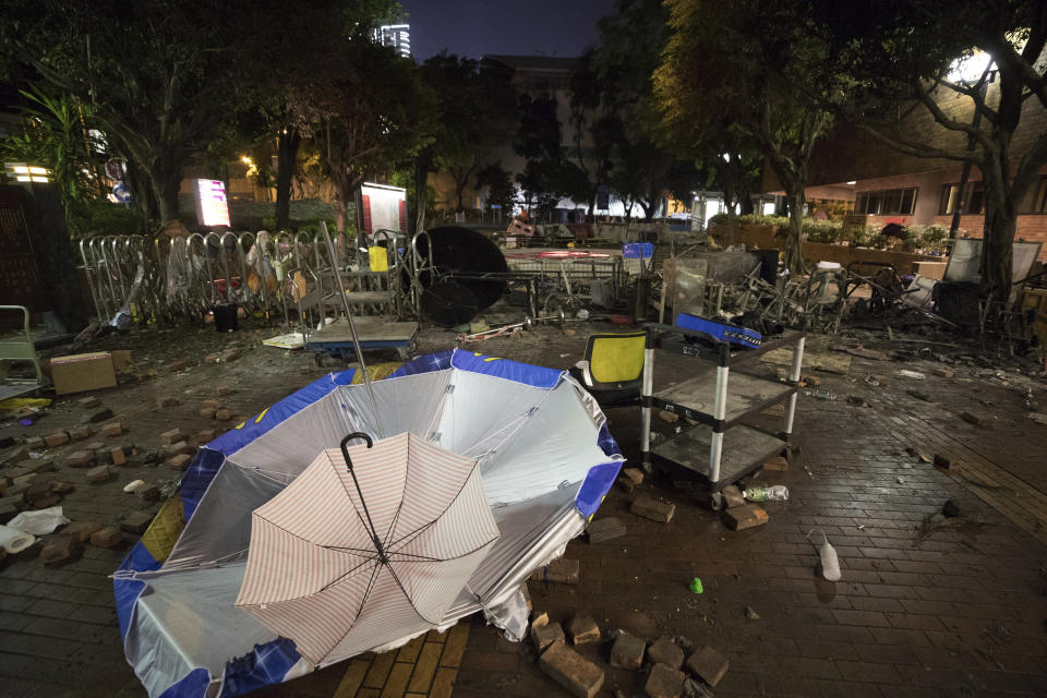 In this Thursday, Nov. 21, 2019, photo, broken umbrellas are left at the entrance of the Hong Kong Polytechnic University campus in Hong Kong. Most of the protesters who took over the university have left following clashes with police, but an unknown number have remained inside, hoping somehow to avoid arrest. (AP Photo/Vincent Thian)