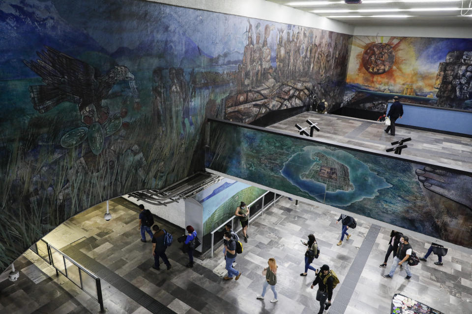 People walk under murals representing the foundation of the Aztec capital city of Tenochtitlan, in the Tacubaya metro station in Mexico City, Tuesday, May 18, 2021. The capital of the Aztec empire, now known as Mexico City, fell to Spanish Conquistador Hernan Cortes after a prolonged siege 500 years ago, marking one of the few times an organized Indigenous army under local command fought European colonizers to a standstill for months, and the final defeat helped set the template for much of the conquest and colonization that came afterward. (AP Photo/Eduardo Verdugo)