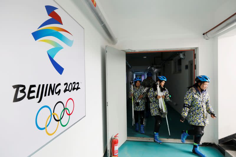 Students leaving an equipment room are seen next to a Beijing 2022 emblem at a middle school in Zhangjiakou