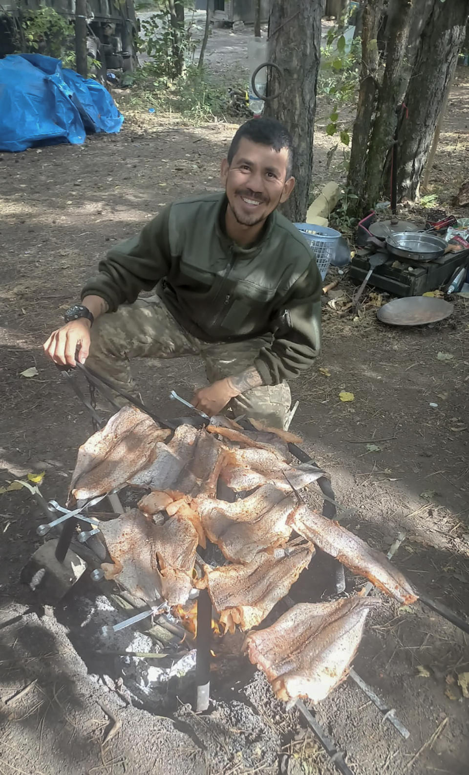 This 2023 photo provided by Oscar Triana's Colombian comrade, who uses the call sign Oso Polar, shows Triana, a retired soldier from Bogotá who joined the Ukrainian army in August 2023, cooking on the front line in the Donetsk region, Ukraine. Oso Polar was the last person to see Triana alive on October 8, 2023. He says Triana’s unit was ambushed by Russian forces in the Kharkiv region, after which his fate was unknown. The Ukrainian military unit where Triana was serving confirmed to AP that Triana is officially missing, but would not disclose any details surrounding the circumstances in which he disappeared. (Oso Polar via AP)