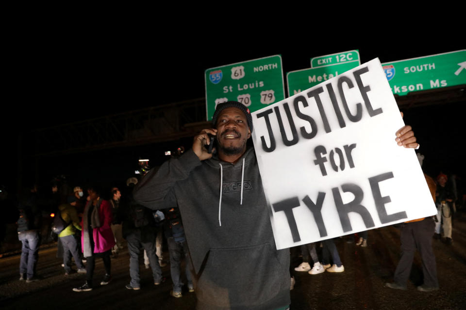 A protester stands on a highway under green highway signs to St. Louis and Jackson Ms.