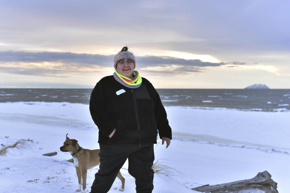 In this Jan. 14, 2019 photo, Clarice "Bun" Hardy stands on the beach with her dog, Marley, in the Native Village of Shaktoolik, Alaska. Hardy, a former 911 dispatcher for the Nome Police Department, says she moved back to her village after a sexual assault left her feeling unsafe in Nome. (AP Photo/Victoria Mckenzie)