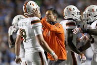 Miami head coach Manny Diaz, center, consoles quarterback Tyler Van Dyke (9) following an NCAA college football game against North Carolina in Chapel Hill, N.C., Saturday, Oct. 16, 2021. (AP Photo/Gerry Broome)