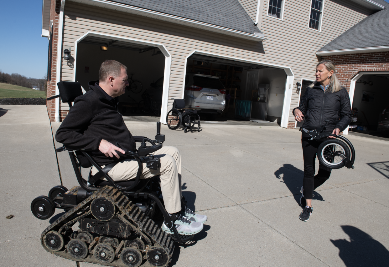 Jason Kolb rides his all-terrain wheelchair, called Action Trackchair, in the driveway of his Kent home while his wife, Amy, watches. He uses the special chair to get to his mother's and brother's nearby homes that abut his property and plans to take it on family vacations.