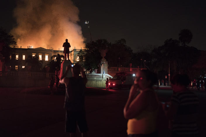People watch as flames engulf the 200-year-old National Museum of Brazil, in Rio de Janeiro, Sunday, Sept. 2, 2018. According to its website, the museum has thousands of items related to the history of Brazil and other countries. The museum is part of the Federal University of Rio de Janeiro (AP Photo/Leo Correa)