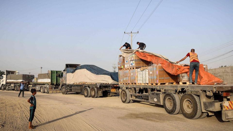 PHOTO: People unload humanitarian aid on a convoy of lorries entering the Gaza Strip from Egypt via the Rafah border crossing on Oct. 21, 2023. (Eyad Baba/AFP via Getty Images)