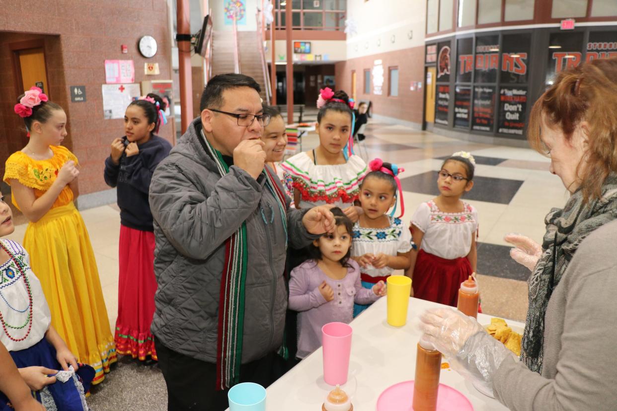 Dany Gomez samples a salsa-dipped chip during the competition as part of Salsa Saturday on Jan. 28, 2023, as several children watch for his reaction.
