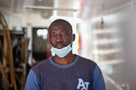 Ibrahima Mbaye, 41, from Senegal, poses for a photo on the deck of the "Vincenzo Padre" fishing boat where he works as fisherman, in the Island of Lampedusa, southern Italy, Thursday, May 13, 2021. The tiny island of Lampedusa, which is closer to Africa than the Italian mainland, is in the throes of yet another season of migrant arrivals, and Mbaye and his fellow countryman Waly Sarr can only watch from shore as their fellow African countrymen risk their lives to get here via smugglers' boats. (AP Photo/Salvatore Cavalli)