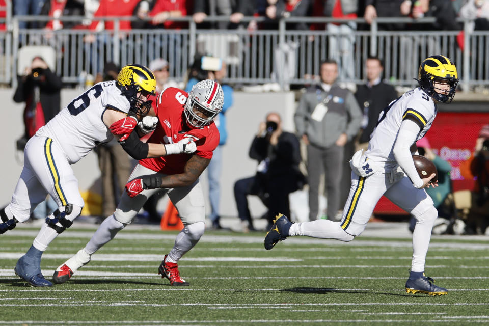 Michigan quarterback J.J. McCarthy, right, scrambles away from Ohio State defensive lineman Zach Harrison during the first half of an NCAA college football game on Saturday, Nov. 26, 2022, in Columbus, Ohio. (AP Photo/Jay LaPrete)