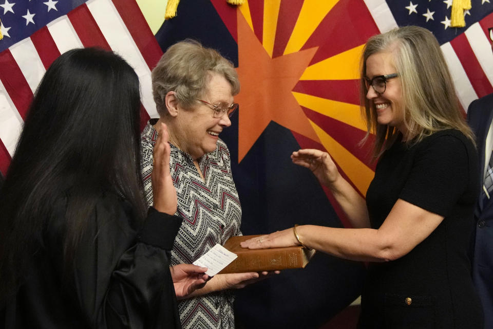 The new Arizona Democratic Gov. Katie Hobbs, right, pauses during taking the oath of office in a ceremony as she laughs with her mother Linda Hobbs, who was emotional in the moment, as U.S. Circuit Judge for the Ninth Circuit Court of Appeals Roopali Desai, left, administers the oath at the state Capitol in Phoenix, Monday, Jan. 2, 2023. (AP Photo/Ross D. Franklin, Pool)