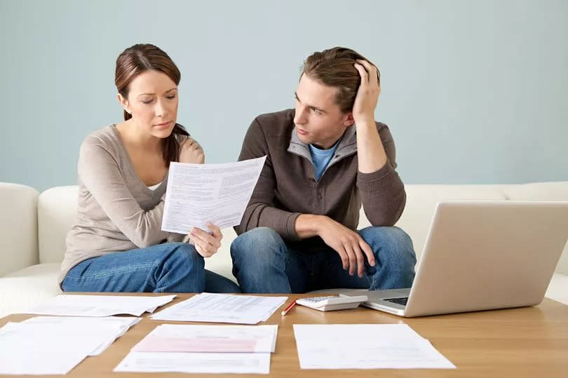 A young couple looking at paperwork and worrying about paying the bills