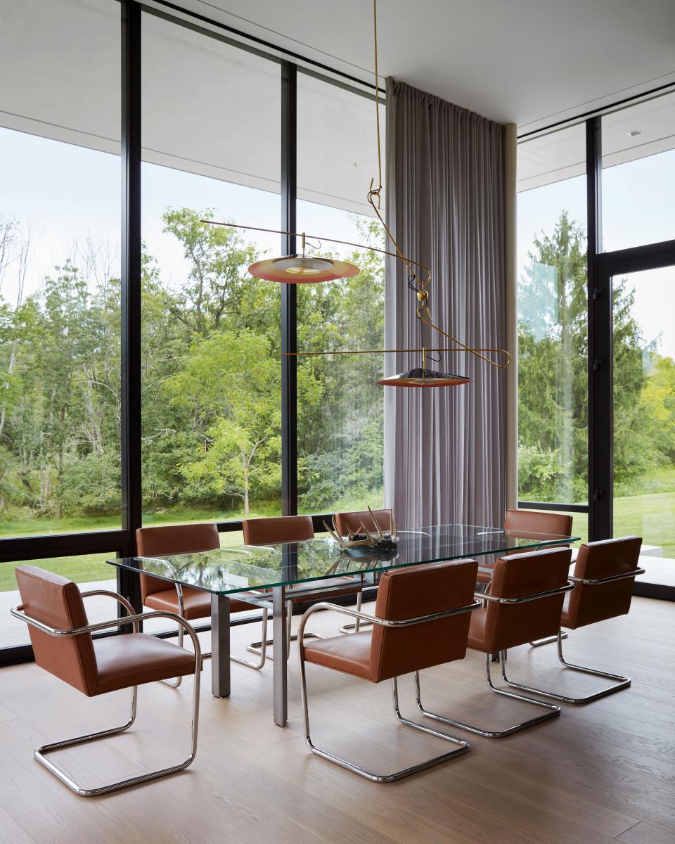 Knoll leather Brno chairs surround a Carlo Scarpa table. A David Weeks enameled metal lighting fixture seems suspended in the trees.