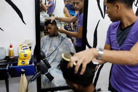 A man gets a haircut after paying for it with two packages of corn flour in Caracas, Venezuela June 29, 2018. Picture taken June 29, 2018. REUTERS/Marco Bello