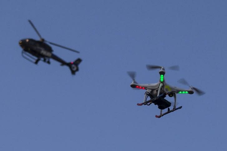 A police helicopter flies past a UAV drone Quadcopter which in west Baltimore, Maryland May 2, 2015. REUTERS/Adrees Latif