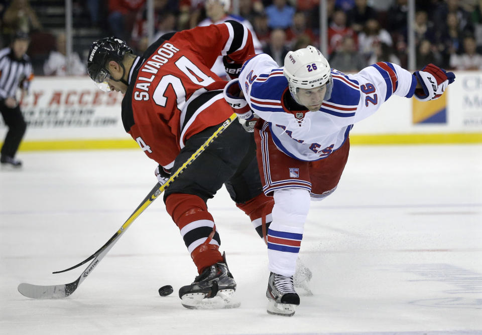 New Jersey Devils' Bryce Salvador (24) gets tied up with New York Rangers' Martin St. Louis (26) during the first period of an NHL hockey game game Saturday, March 22, 2014, in Newark, N.J. (AP Photo/Mel Evans)