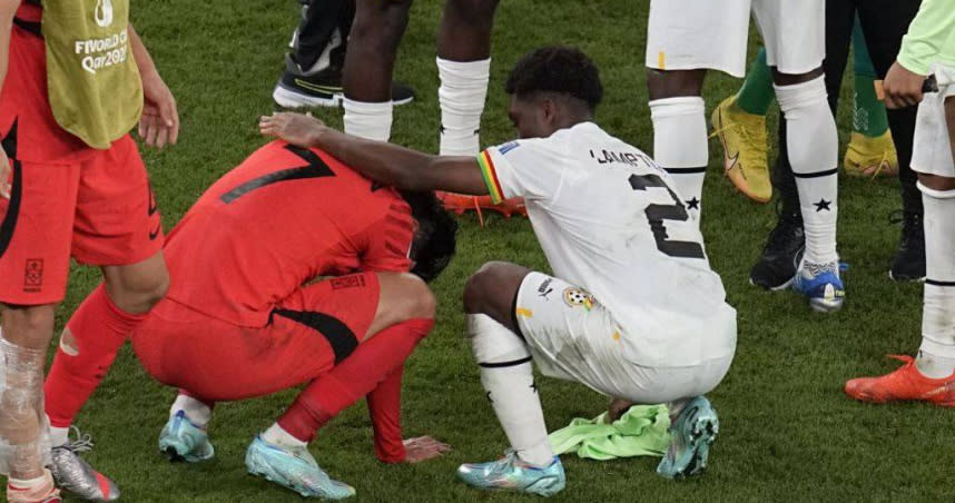 南韓落敗後，隊長孫興慜在場上痛哭，一堆迦納球員與教練團成員上前安慰。（圖／達志／美聯社）