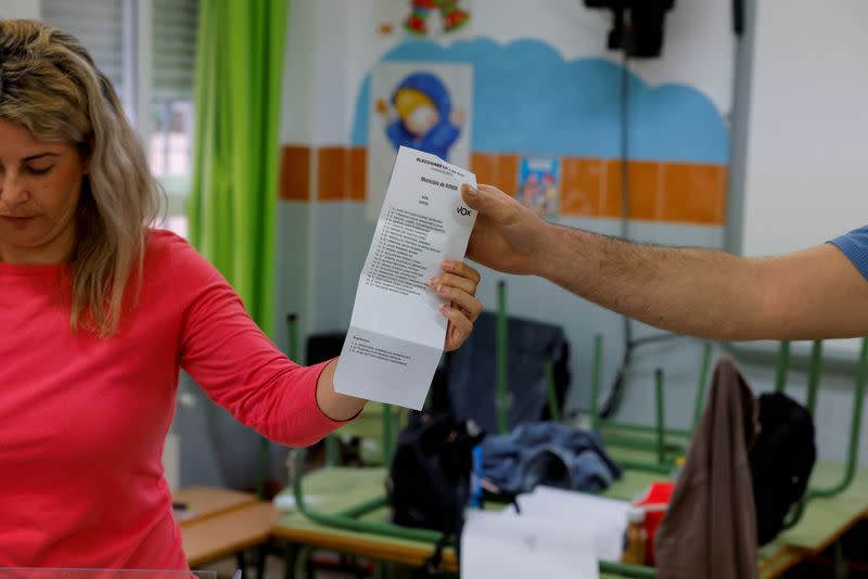 Members of an electoral table hold a ballot of the Spanish far-right party Vox as they count the ballots of the local elections, in Ronda