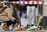 A woman sets a candle near the hookah bar scene where several people were killed late Wednesday in Hanau, Germany, Thursday, Feb. 20, 2020. A 43-year-old German man shot and killed several people at different locations in a Frankfurt suburb overnight in attacks that appear to have been motivated by far-right beliefs, officials said Thursday. (AP Photo/Martin Meissner)