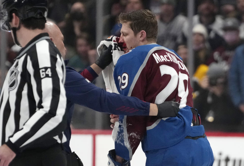 A trainer tends to Colorado Avalanche center Nathan MacKinnon after he collided with Boston Bruins left wing Taylor Hall (71) and fell to the ice in the first period of an NHL hockey game Wednesday, Jan. 26, 2022, in Denver. (AP Photo/David Zalubowski)