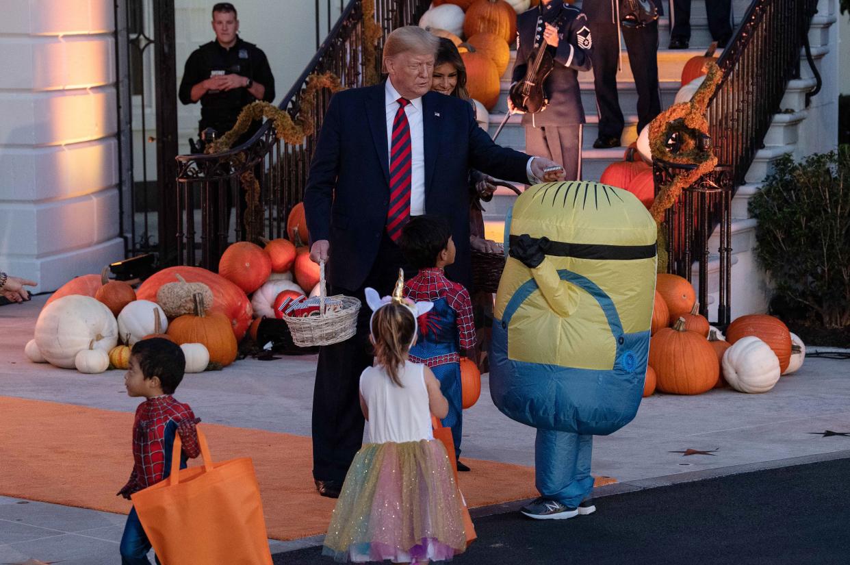 President Donald Trump and First Lady Melania Trump hand out candy for children at a Halloween celebration at the White House. (Photo: Nicholas Kamm via Getty Images)