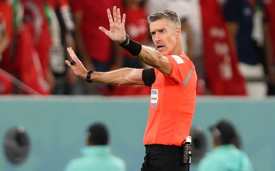 Referee Matthew Conger waits for news through his ear piece before heading swiftly to the pitchside monitor - Tolga Bozoglu/Shutterstock