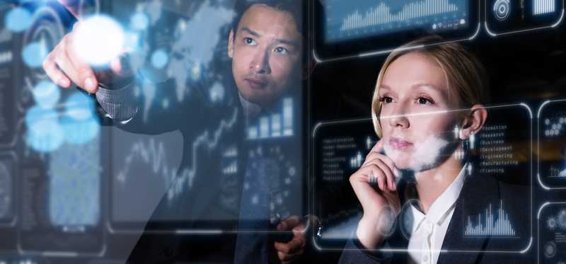 A male and female in suits interacting with a digital touch screen.