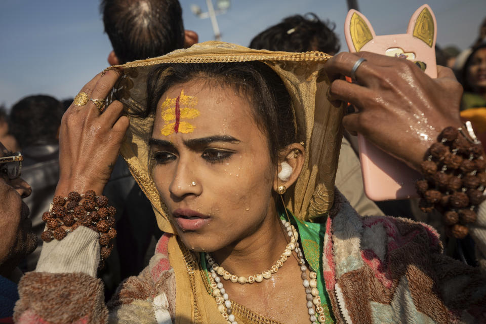 In this Jan. 15, 2019, photo, an Indian hijra walks on the banks after taking a dip along with other members of the newly formed "Kinnar akhara" monastic order on the auspicious Makar Sankranti day during the Kumbh Mela festival in Prayagraj, Uttar Pradesh state, India. Unlike other akharas, which are only open to Hindu men, Kinnar, founded in 2015, is open to all genders and religions. This is the first time the newly formed Kinnar Akhara, or monastic order, has set up camp at the massive temporary city in Prayagraj, led by transgender activist Laxmi Narayan Tripathi. (AP Photo/Bernat Armangue)