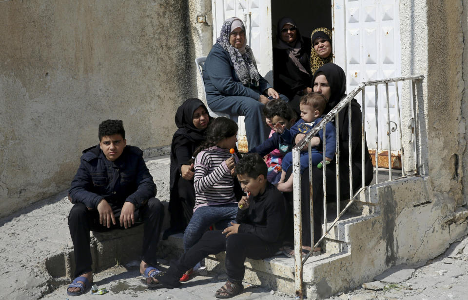 In this Wednesday, March 27, 2019 photo, relatives of Palestinian groom Walid al-Shawa, sit in front of the rubble of a building that was destroyed in an Israeli airstrike Monday, in Gaza City. Al-Shawa was due to get married in two weeks, but an Israeli airstrike on a Gaza City building destroyed his sister's apartment, where he had rented a second floor bedroom and had amassed everything he and his bride needed for the wedding. (AP Photo/Adel Hana)