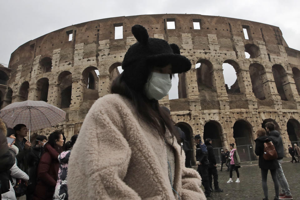 A tourist, part of a group coming from Shanghai, China, wears a mask as she visits Rome's ancient Colosseum, Saturday, Feb. 1, 2020. Italy banned all flights coming from and going to China as European countries have stepped up their response to the new virus that has sickened thousands of people in China and reached 19 other countries. Italy has reported two cases. (AP Photo/Alessandra Tarantino)