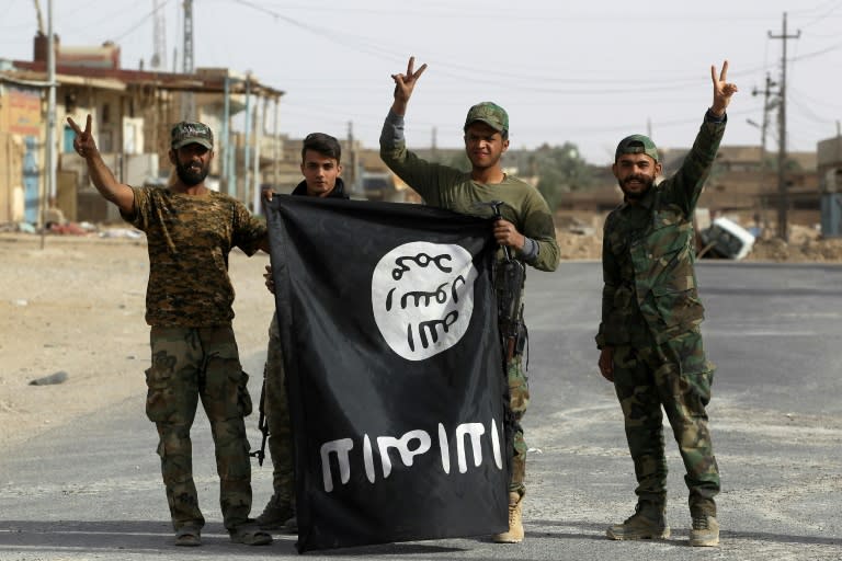 Members of Iraq's Hashed al-Shaabi (Popular Mobilisation units) carry an upsidedown Islamic State group flag in Al-Qaim on November 3, 2017