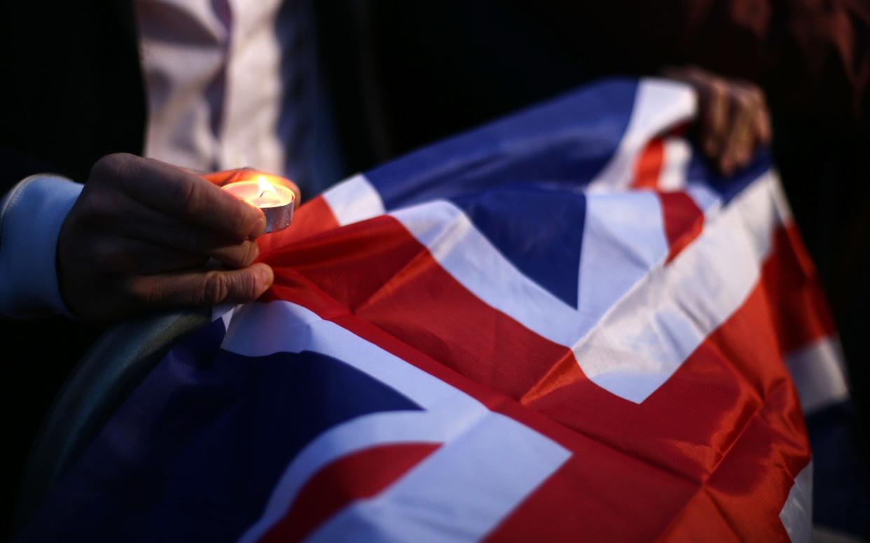 A member of the public holds a candle and Union Jack flag during the candlelight vigil in Trafalgar Square, London to remember those who lost their lives in the Westminster terrorist attack. - Yui Mok/PA Wire