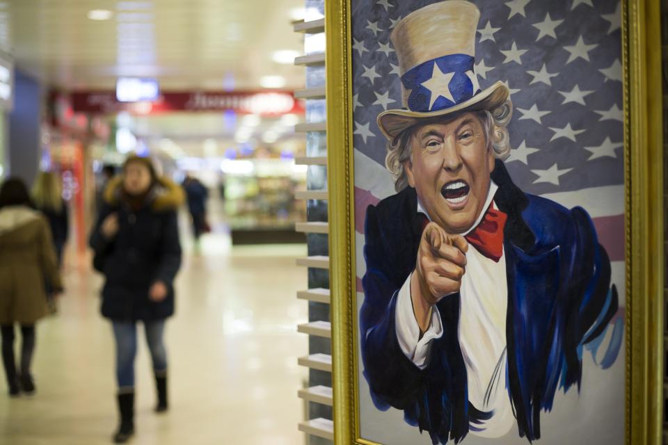 FILE- In this file photo taken on Wednesday, March 22, 2017, People walk past a caricature picture of U.S. President Donald Trump on sale in a shopping mall in Moscow, Russia. US President Trump's new executive sanctions order signed Wednesday Sept. 12, 2018, authorizing sanctions on foreigners who mess with American elections could herald new headaches for Moscow. (AP Photo/Alexander Zemlianichenko)