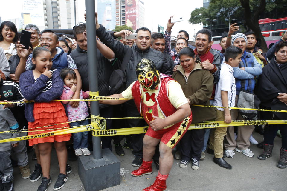 Mexican wrestler Pinochito poses with the crowd during a "lucha libre" fight in Mexico City, Saturday, Dec. 21, 2019. Mexican wrestling, otherwise known as the “lucha libre,” is a highly traditional form of light entertainment. (AP Photo/Ginnette Riquelme)
