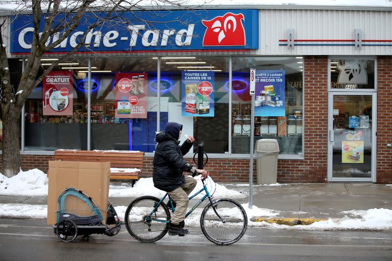 FILE PHOTO: A man cycles past a Couche-Tard convenience store in Montreal