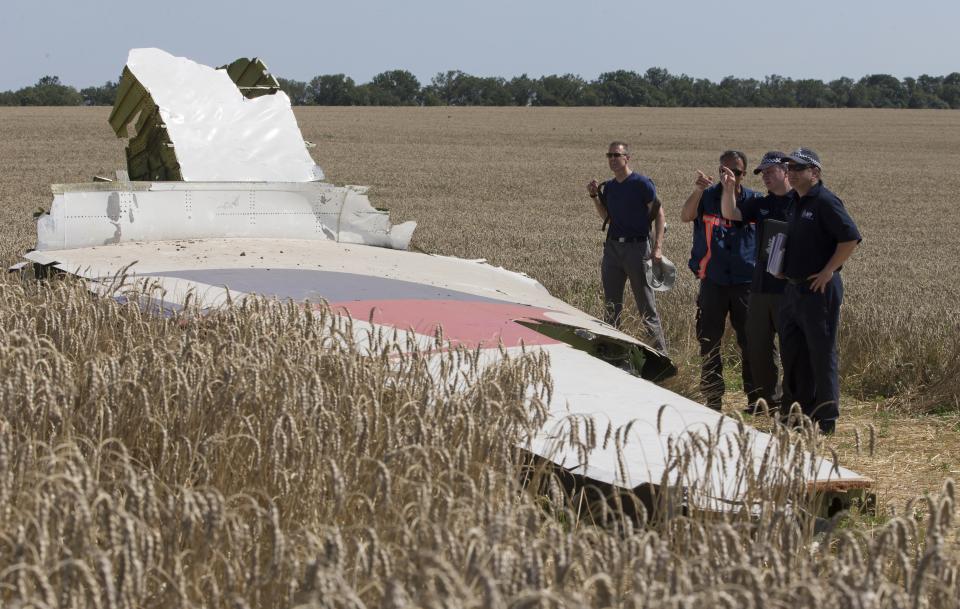 FILE - In this Friday, Aug. 1, 2014 file photo, Australian and Dutch investigators examine a piece of the Malaysia Airlines Flight 17 plane, near the village of Hrabove, Donetsk region, eastern Ukraine. The Dutch government is taking to Russia to the European Court of Human Rights for its alleged role in the shooting down of Malaysia Airlines Flight 17 over eastern Ukraine six years ago, the foreign minister announced Friday July 10, 2020.(AP Photo/Dmitry Lovetsky, File)