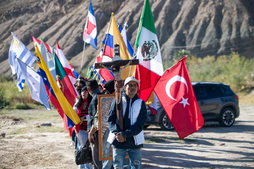 Migrants carrying flags get ready for a mass given by the catholic clergy of Las Cruces, New Mexico, El Paso, Texas, and Ciudad Juarez, Chihuahua in the middle of the river on Nov. 4, 2023.