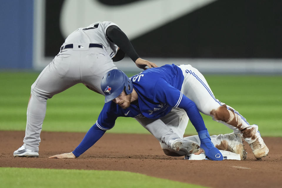 Toronto Blue Jays' Danny Jansen, right, is ruled safe at second base against New York Yankees second baseman Gleyber Torres, left, after a review during seventh-inning baseball game action in Toronto, Monday, Sept. 26, 2022. (Nathan Denette/The Canadian Press via AP)