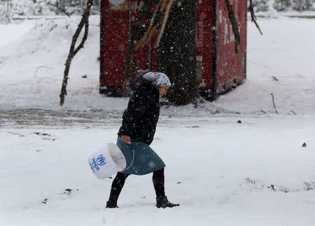 A stranded Syrian refugee braves a snowstorm at a refugee camp north of Athens, Greece January 10, 2017.REUTERS/Yannis Behrakis