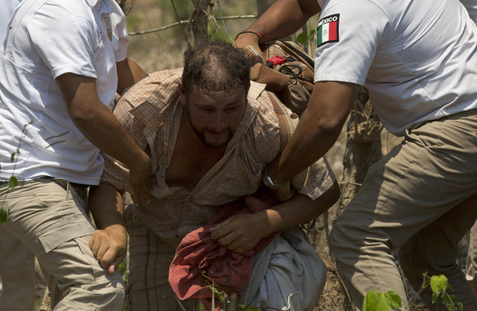 Un migrante centroamericano es detenido por agentes de inmigración mexicanos en la carretera a Pijijiapan, México, el lunes 22 de abril de 2019. La policía mexicana y los agentes de inmigración detuvieron a cientos de migrantes centroamericanos el lunes en la mayor redada de una caravana de migrantes desde que comenzaron a movilizarse a través de México el año pasado. (AP Foto/Moisés Castillo)