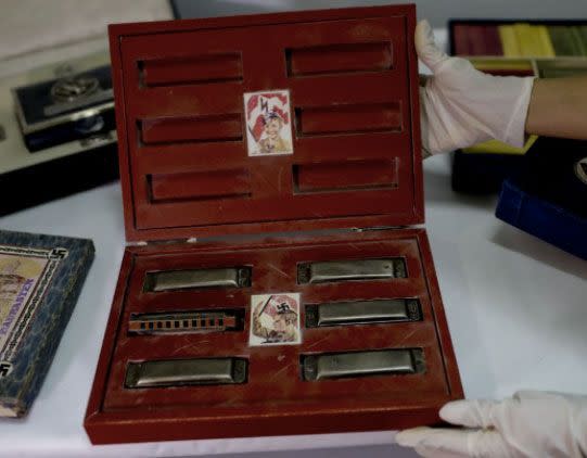 A member of the federal police shows a box with swastikas containing harmonicas for children at the Interpol headquarters in Buenos Aires. Source: AP Photo/Natacha Pisarenko