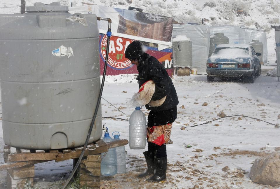 A Syrian refugee carries bread and bottles of water during a winter storm in Zahle town, in the Bekaa Valley December 11, 2013. The worst of winter is yet to come for 2.2 million refugees living outside Syria and millions more displaced inside the country. A storm named Alexa is sweeping across Syria and Lebanon, bringing with it high winds and freezing temperatures - and marking the beginning of the third winter since the Syrian conflict began in March 2011. In the tented settlement a few kilometres from the border in Lebanon's Bekaa Valley, more than 1,000 people live in rudimentary shelters. REUTERS/Mohamed Azakir (LEBANON - Tags: POLITICS CIVIL UNREST CONFLICT SOCIETY IMMIGRATION ENVIRONMENT)