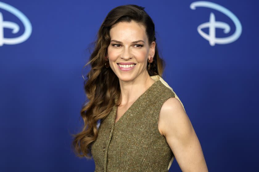 A woman with long brown hair smiling against a blue background