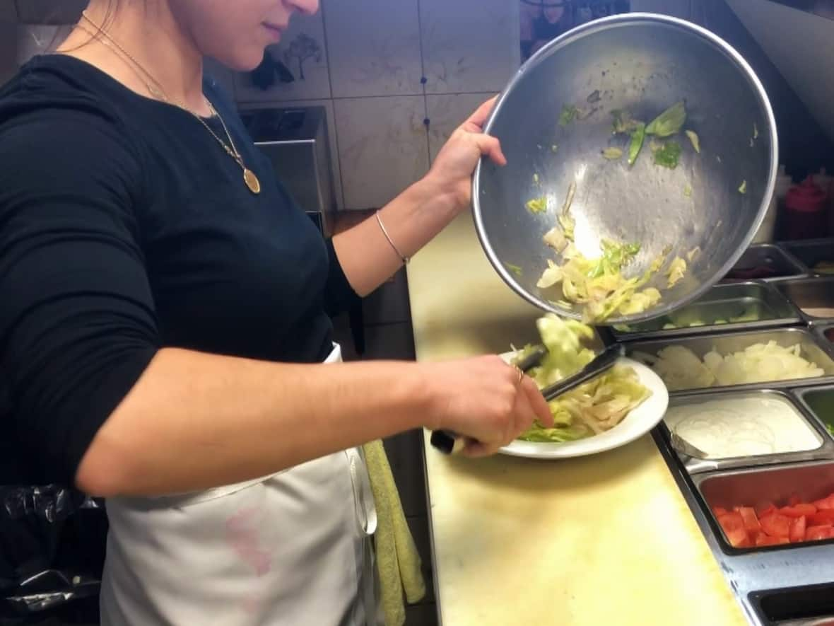 A cook at Nick the Greek restaurant prepares a Greek salad. Manager Charlie Kyriazakos says the cost of a crate of 24 heads of lettuce costed more than $160 last week. (TJ Dhir/CBC - image credit)