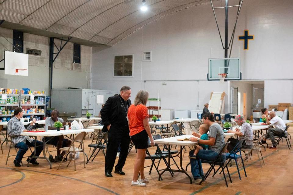 Bishop Louis F. Kihneman III visits with volunteers and people eating lunch provided by Loaves and Fishes at the former Mercy Cross High School in Biloxi on Tuesday, May 14, 2024.