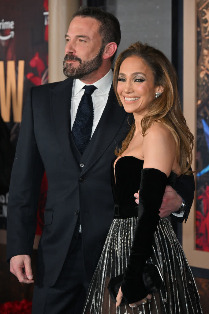 the couple posing; Ben in a suit and Jennifer in an off-shoulder dress with a metallic fringe skirt